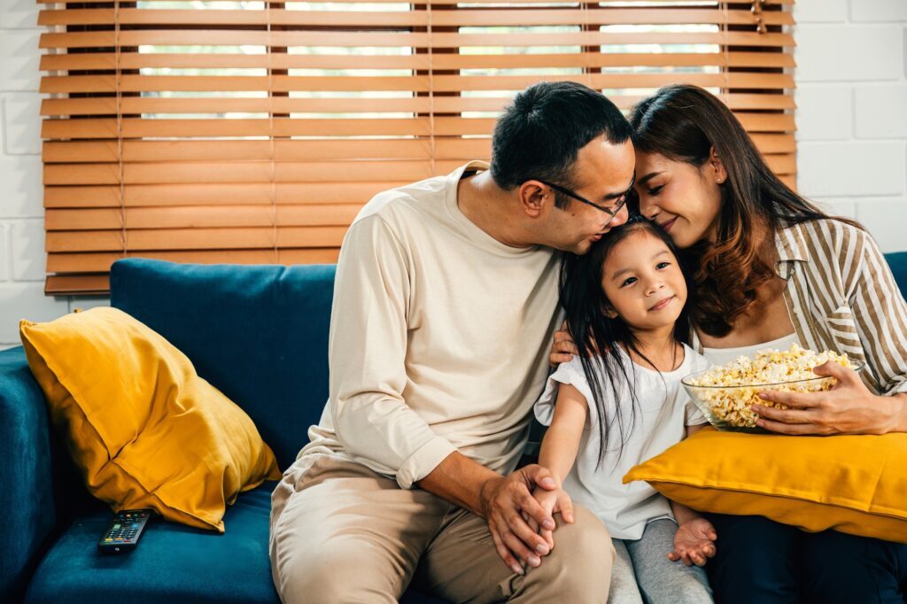 A happy family filled with joy watches TV while eating popcorn on modern sofa at home