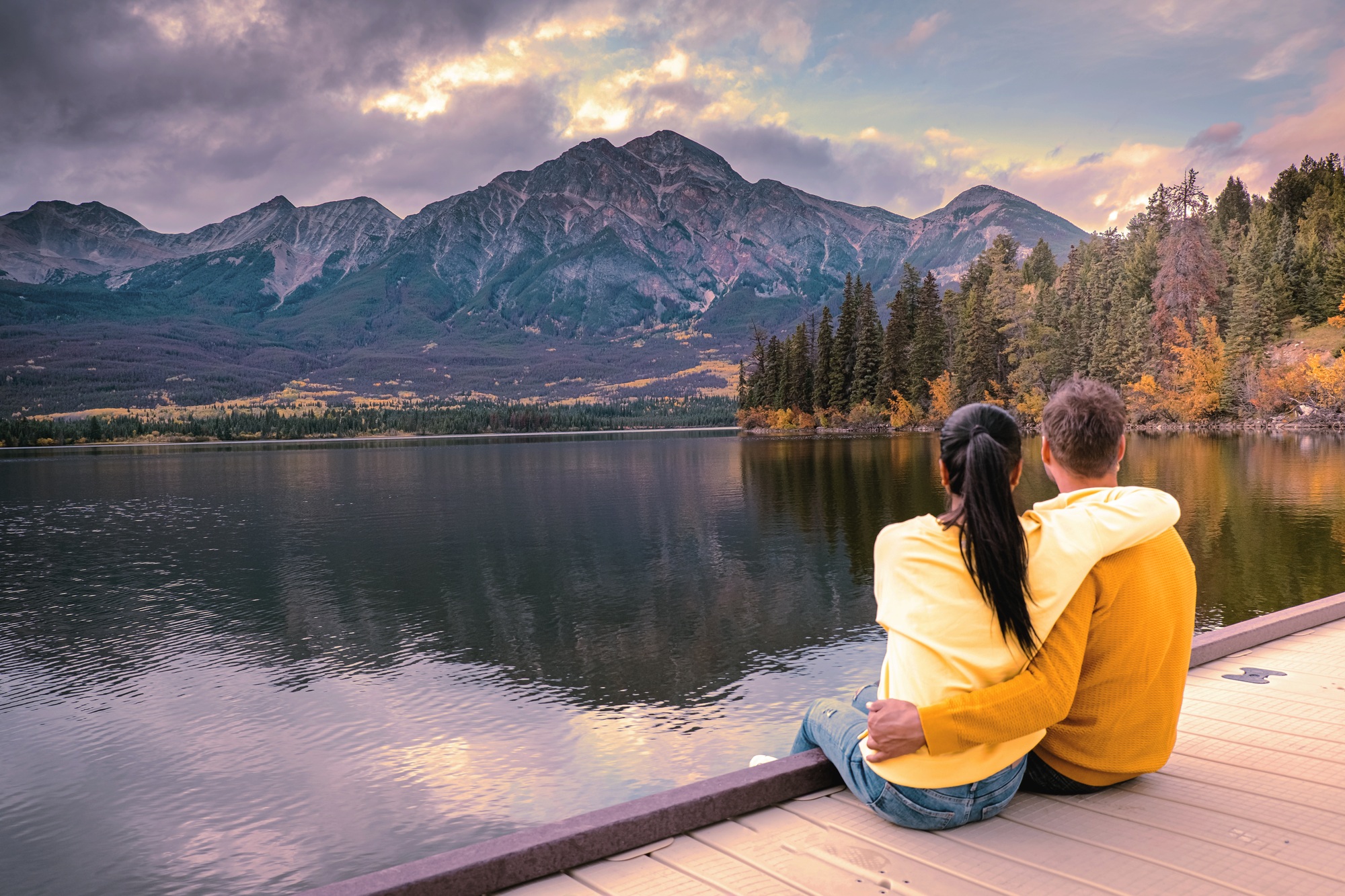 couple by the lake watching sunset, Pyramid lake Jasper during autumn in Alberta Canada