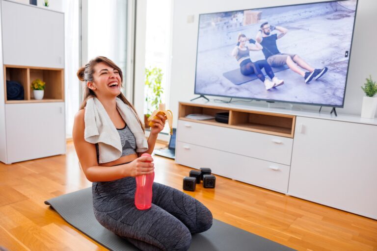 Woman eating banana and drinking water while taking a home workout break