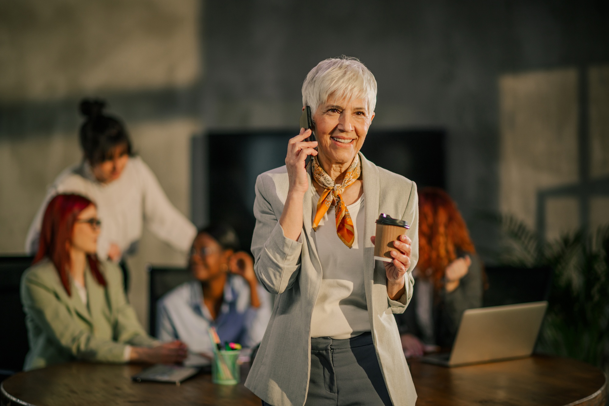 Senior executive with coffee having a phone conversation at the office