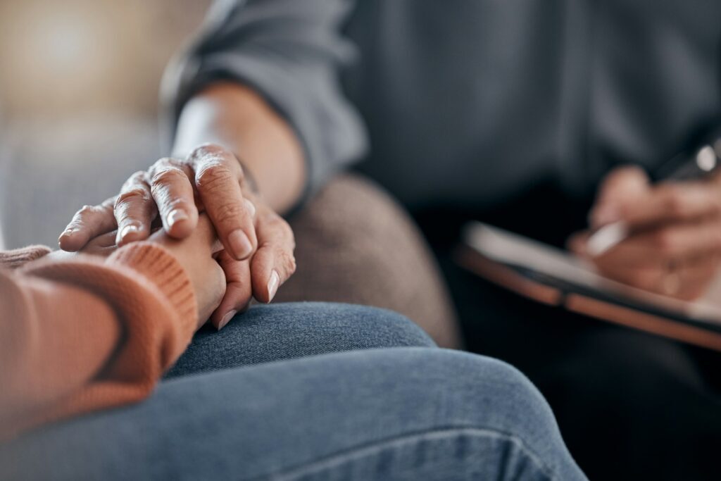 Closeup, hands and support in therapy, conversation and grief with compassion, empathy or support.