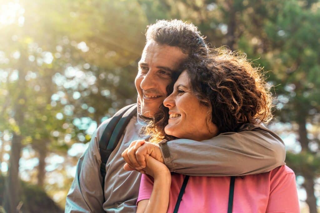 Happy mature couple embracing outdoors in sunlight, romance and togetherness