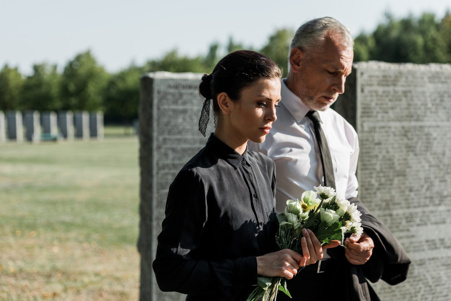 bearded senior man near woman with flowers on funeral