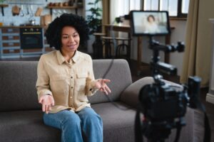 Black African woman millennial female vlogger speaking making video vlog using camera at home