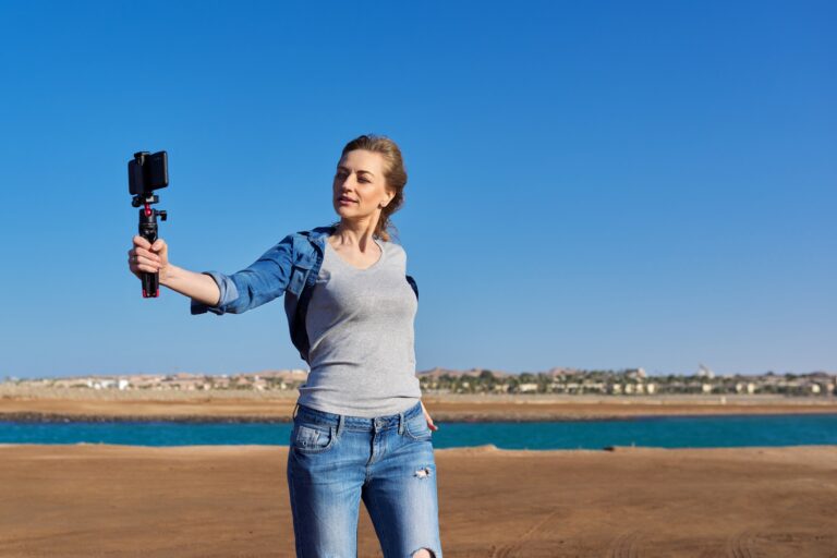 Middle-aged woman recording video on smartphone with outdoor on seashore